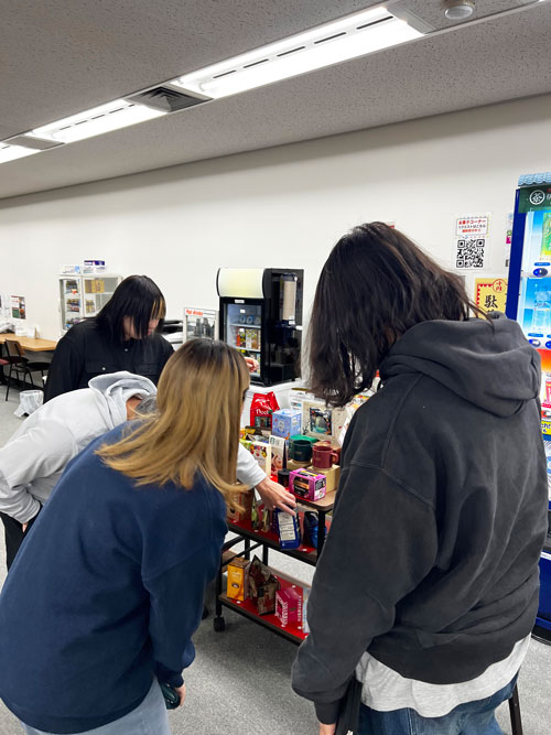 MJカフェの会場に集まり商品をみる従業員