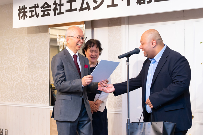 社員からプレゼントを受け取り笑顔の社長