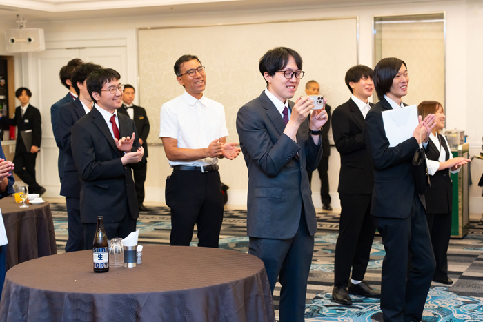 社長と社員のステージ上での様子に笑顔で見届ける社員とそのご家族