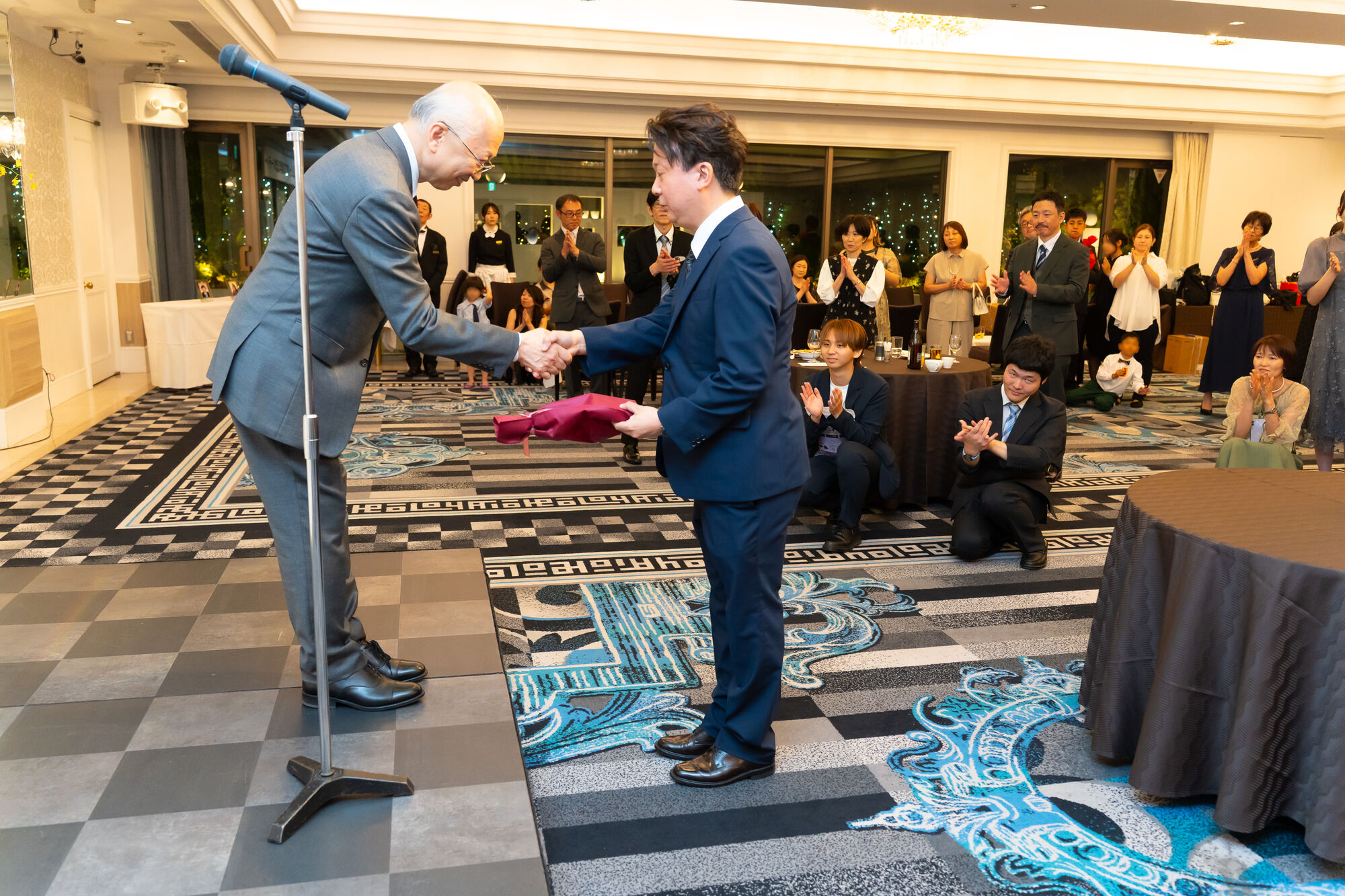 社長の感謝の言葉のあとに堅く握手をする社長と北澤副社長