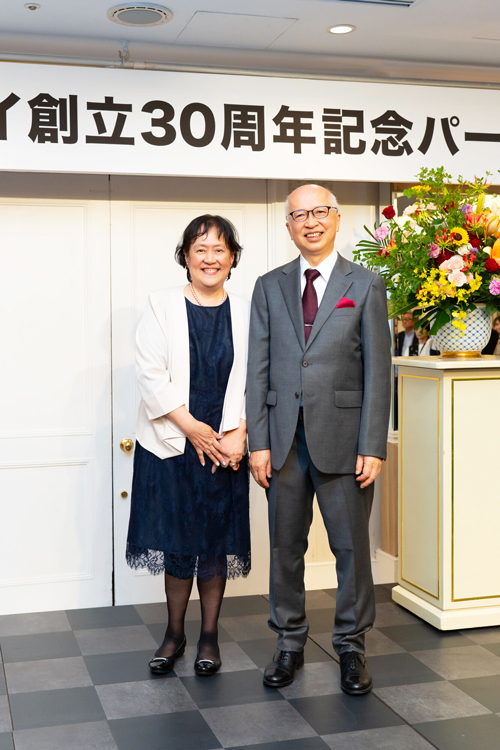二人で並んで記念写真を撮る社長と奥様